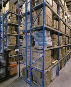 Overview of a large industrial distribution warehouse storing products in cardboard boxes on